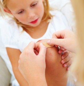 Closeup of a mother putting bandaid to her daughter's knee